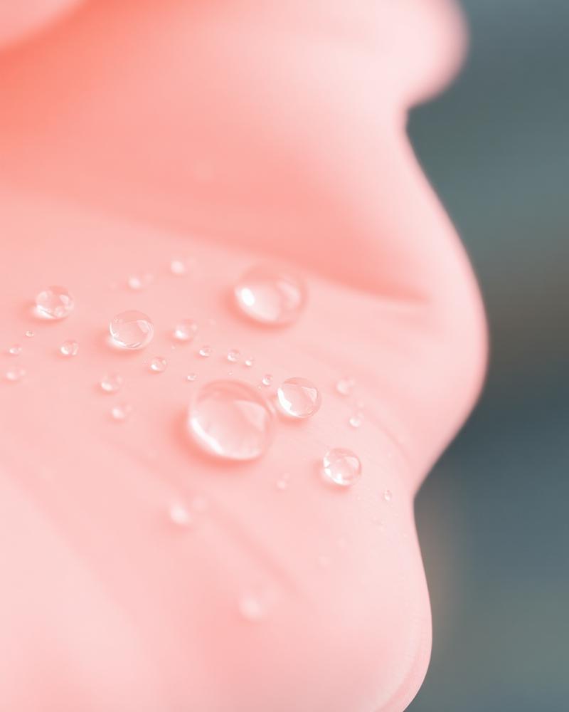 Close-up of dewy water droplets on hydrated skin with warm peach and cream tones.