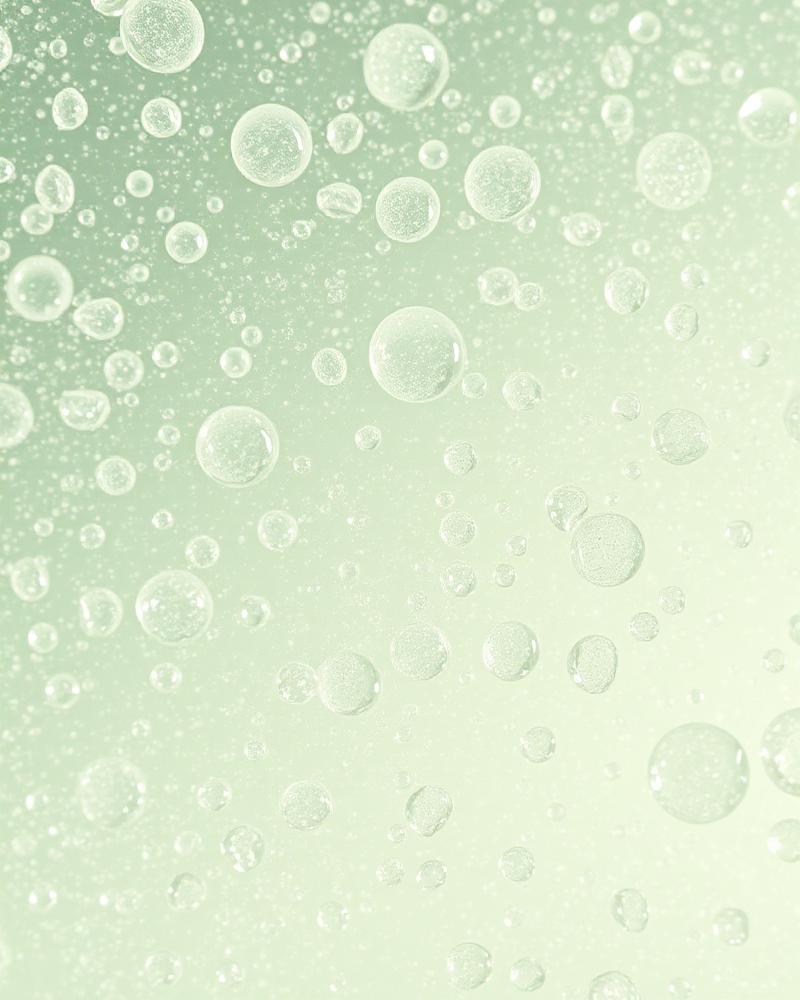 Fresh toner droplets resting on a green leaf with soft sage lighting, evoking balanced oily skincare.